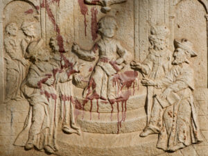 Ein Steinrelief mit mehreren in Gewänder gehüllten Figuren im Gespräch, die mit einer roten, blutähnlichen Flüssigkeit befleckt sind, was eine dramatische und beunruhigende Wirkung auf das Kunstwerk hat. (Text mit KI erstellt)