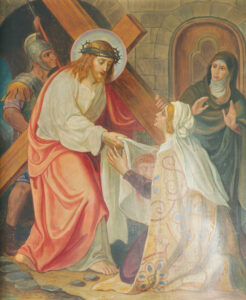 Ein Bild von Jesus, der ein Kreuz trägt und eine Dornenkrone trägt, während er einer knienden Frau begegnet, die ein Tuch hält. Ein römischer Soldat und eine weitere Frau stehen im Hintergrund und zeigen sich besorgt. (Text mit KI erstellt)