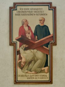 Ein religiöses Gemälde zeigt Jesus, der zum dritten Mal unter das Kreuz fällt, während zwei Männer über ihm wachen. Über und unter der Szene ist ein deutscher Text auf einem kreuzförmigen Rahmen zu lesen. (Text mit KI erstellt)