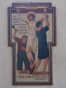 Eine gemalte Darstellung der Kreuzigung Jesu, die zwei Männer zeigt, die seine Hände und Füße an das Kreuz nageln. Der deutsche Text beschreibt die Szene: Jesus wird an das Kreuz genagelt. Sie haben meine Hände und Füße durchbohrt. (Text mit KI erstellt)