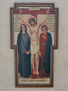 Eine gemalte Darstellung von Jesus am Kreuz mit einem Heiligenschein, flankiert von zwei trauernden Figuren. Ein deutscher Text umgibt die Szene: "Jesus stirbt am Kreuze" und verweist auf die Liebe Gottes zur Welt. (Text mit KI erstellt)