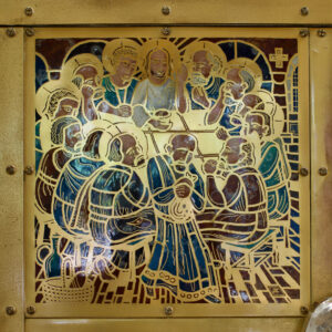 Das Kunstwerk aus Gold und Emaille zeigt Jesus und seine zwölf Jünger beim Letzten Abendmahl, die um einen Tisch sitzen. Die Gesichter und Gesten der Jünger sind durch feine Linien und Details hervorgehoben. (Text mit KI erstellt)