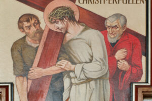 Religiöses Gemälde von Jesus, der ein Holzkreuz mit einer Dornenkrone trägt, flankiert von zwei Männern - einer in rotem Gewand und mit strenger Miene, der andere hilft, das Kreuz anzuheben. (Text mit KI erstellt)