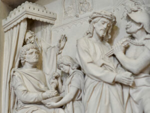 Marmorrelief mit einer biblischen Szene: Ein Mann wäscht sich die Hände in einer Schale, die von einem Jungen gehalten wird, während andere zusehen, darunter eine Figur mit Dornenkrone und Soldaten in Rüstung. (Text mit KI erstellt)