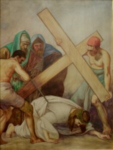 Ein Gemälde zeigt Jesus, der unter dem Gewicht eines großen Holzkreuzes zusammenbricht, während drei Männer um ihn herumstehen, von denen zwei das Kreuz stützen und einer ihn hochzuziehen scheint. Die Szene ist düster und ausdrucksstark. (Text mit KI erstellt)