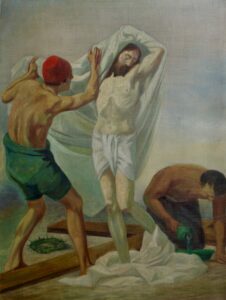 Ein Gemälde zeigt drei Männer; einer ist fast nackt mit erhobenen Armen und wird von einem anderen Mann mit einer roten Mütze in ein weißes Tuch gehüllt, während ein dritter Mann kniet und Wasser auf ein Holzbrett gießt. Eine Dornenkrone liegt auf dem Boden. (Text mit KI erstellt)