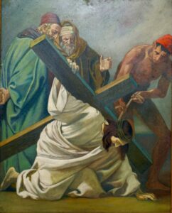 Ein Gemälde zeigt Jesus, der mit einem großen Holzkreuz und einer Dornenkrone auf dem Kopf stürzt. Zwei Männer in Gewändern stehen hinter ihm, und ein weiterer Mann mit einer roten Mütze hilft, das Kreuz anzuheben. (Text mit KI erstellt)