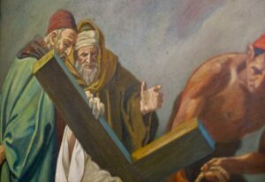 Ein Bild von zwei älteren Männern in Gewändern und mit Kopfbedeckung, von denen einer ein großes Holzkreuz trägt, während ein anderer muskulöser Mann mit nacktem Oberkörper daneben steht. Die Szene wirkt angespannt und dramatisch. (Text mit KI erstellt)