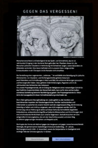 Eine deutschsprachige Museumsausstellung mit dem Titel "GEGEN DAS VERGESSEN!" zeigt ein Steinrelief mit einer abwertenden mittelalterlichen Darstellung und einem erklärenden Text über antisemitische Bilder und die Bedeutung des Gedenkens. (Text mit KI erstellt)