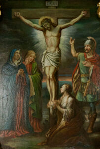 Ein Gemälde von Jesus am Kreuz mit Heiligenschein, umgeben von drei Trauernden und einem römischen Soldaten; eine Frau kniet zu seinen Füßen, während die beiden anderen stehen und zusehen, wobei die Szene durch eine dramatische Beleuchtung hervorgehoben wird. (Text mit KI erstellt)