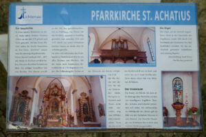 Informationstafel über die Pfarrkirche St. Achatius in Lichtenau mit Texten über die Geschichte, das Innere der Kirche, den Altar und die Orgel sowie fünf Fotos, die verschiedene Ansichten des Kircheninneren und der dekorativen Elemente zeigen. (Text mit KI erstellt)
