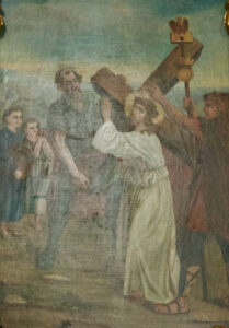 Ein Gemälde zeigt Jesus, der ein großes Holzkreuz trägt und eine Dornenkrone trägt, umgeben von mehreren Figuren, darunter ein Mann, der ihm hilft, und andere, die ihn beobachten. Eine Person hält einen Stab mit einem goldenen Ornament. (Text mit KI erstellt)