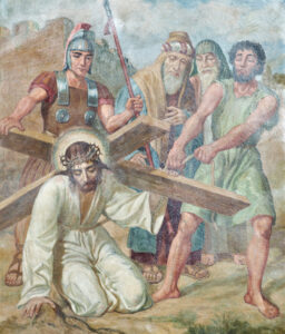 Ein Gemälde zeigt Jesus kniend, ein Holzkreuz tragend und mit einer Dornenkrone versehen, während ein römischer Soldat und drei weitere Männer hinter ihm stehen, von denen zwei ihn zu drängen scheinen. (Text mit KI erstellt)