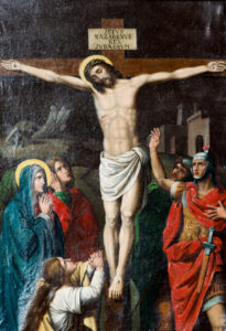 Ein Gemälde von Jesus am Kreuz, der eine Dornenkrone trägt, mit einem Zeichen über seinem Kopf. Darunter stehen vier Trauernde und ein römischer Soldat, die Trauer und Verzweiflung ausdrücken. Im Hintergrund sind antike Gebäude zu sehen. (Text mit KI erstellt)