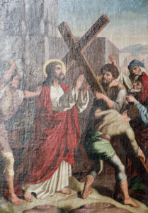 Ein Gemälde zeigt Jesus mit Heiligenschein und rotem Gewand, der ein Holzkreuz trägt und von mehreren Männern umgeben ist; einige helfen ihm, andere scheinen ihn zu verhöhnen oder anzuschreien. Im Hintergrund sind Gebäude und Berge zu sehen. (Text mit KI erstellt)