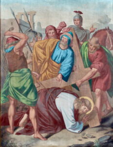 Ein Gemälde zeigt Jesus, der ein Holzkreuz trägt, umgeben von römischen Soldaten und Anhängern. Jesus ist zu Boden gefallen und trägt eine Dornenkrone und einen Heiligenschein, während andere ihm entweder beistehen oder ihn verhöhnen. (Text mit KI erstellt)