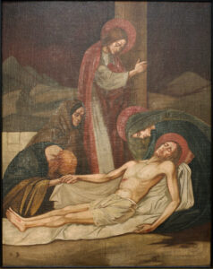 Ein Gemälde zeigt drei Trauernde um den leblosen Körper Jesu, der auf einem weißen Tuch liegt. Zwei Figuren tragen dunkle Gewänder; eine beugt sich mit einem roten Heiligenschein über ihn, eine andere steht hinter ihr, ebenfalls mit einem Heiligenschein. Im Hintergrund sind Berge und ein gedämpfter Himmel zu sehen. (Text mit KI erstellt)