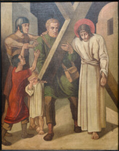 Ein Gemälde zeigt Jesus, wie er, von einem Mann unterstützt, ein Kreuz trägt, während zwei Kinder und ein Soldat zusehen. Jesus hat einen Heiligenschein und wirkt erschöpft. Die Szene spielt sich im Freien ab, im Hintergrund sind Gebäude zu sehen. (Text mit KI erstellt)
