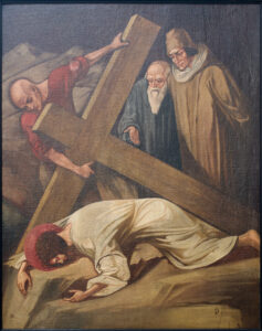 Ein Gemälde zeigt Jesus, wie er unter einem großen Holzkreuz auf felsigem Boden liegt; er trägt ein weißes Gewand und eine Dornenkrone. Drei Männer stehen in der Nähe; einer hilft dabei, das Kreuz hochzuheben, und zwei andere schauen zu, gekleidet in Gewänder alter Zeit. (Text mit KI erstellt)