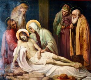 Ein Gemälde zeigt Jesus nach der Kreuzigung, wie er auf Marias Schoß liegt, umgeben von Trauernden. Zwei Figuren halten eine Dornenkrone in den Händen, während andere voller Trauer zusehen. Jesus und Maria sind mit goldenen Heiligenscheinen umgeben. Die Szene wirkt feierlich und bewegend. (Text mit KI erstellt)