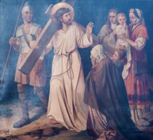 Ein Mann, der ein Holzkreuz trägt, ein Gewand und einen Heiligenschein, ist von Soldaten und Frauen umgeben, darunter eine, die ein Kind im Arm hält. Einige Frauen wirken bewegt, knien nieder oder strecken die Hände nach ihm aus. Die Szene spielt im Freien, die Gesichter wirken ernst. (Text mit KI erstellt)