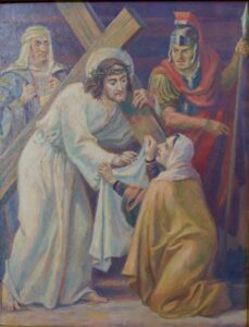 Ein Mann, der ein Holzkreuz trägt, wird von einer knienden Frau angesprochen, die ein Tuch in der Hand hält; zwei weitere Personen, von denen eine eine Rüstung trägt, stehen in der Nähe. Die Szene wirkt angespannt und emotional. (Text mit KI erstellt)