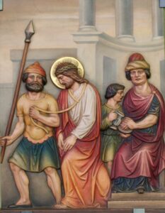 Ein religiöses Gemälde zeigt Jesus mit Heiligenschein, einer Dornenkrone und einem roten Gewand, wie er von drei Männern in antiker Kleidung geführt wird; einer hält einen Speer, ein anderer ein Seil, das um Jesu Hals gebunden ist. Im Hintergrund sind Säulen und Bögen zu sehen. (Text mit KI erstellt)