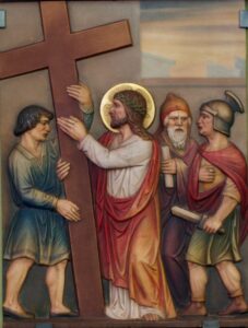 Eine Darstellung von Jesus, der ein Holzkreuz trägt, begleitet von drei Männern – einem, der ihm hilft, einem in Gewändern und mit rotem Hut sowie einem römischen Soldaten, der ein Schwert hält –, vor einem gedämpften Hintergrund. (Text mit KI erstellt)