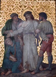 Ein Gemälde, das Jesus in einem weißen Gewand mit Heiligenschein zeigt, umgeben von vier Männern. Zwei Männer halten seine Arme fest, ein weiterer kniet mit einem Beutel in der Hand, und einer steht hinter ihm. Im Hintergrund ist ein goldenes Blumenmuster zu sehen. (Text mit KI erstellt)